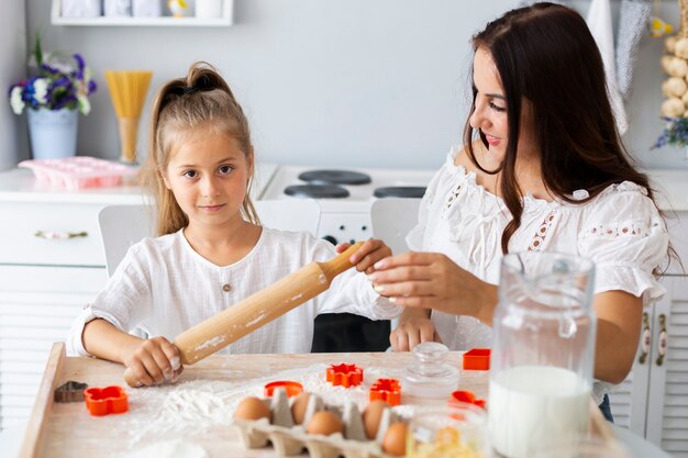 Mother teaching daughter how to use kitchen roller