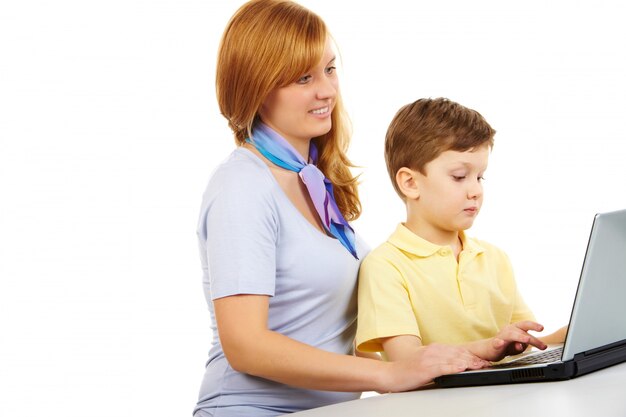 Mother teaching her child to use the laptop