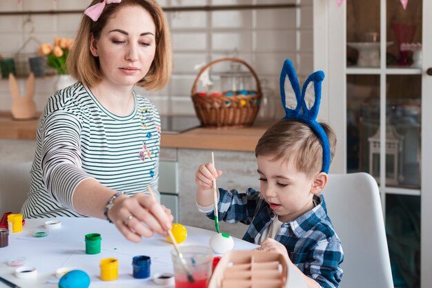Mother teaching little boy how to paint eggs for easter