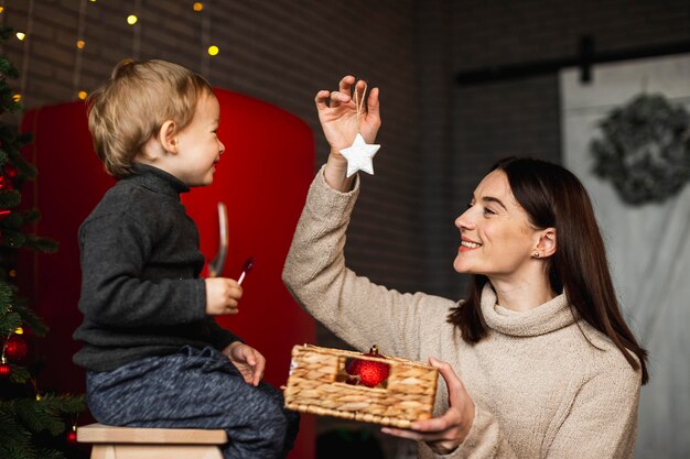 Mother teaching son how to decorate christmas tree