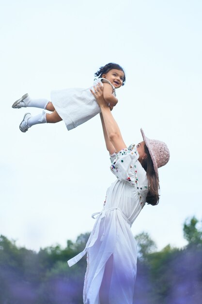 Mother throwing up baby daughter in lavender field