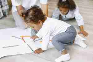 Free photo mother and two afro-american daughters drawing together. adult woman spending time with her little girls.