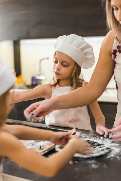 Mother and two daughters preparing cookies in kitchen