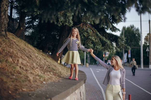 Mother walking holding her daughter's hand and climbing a wall