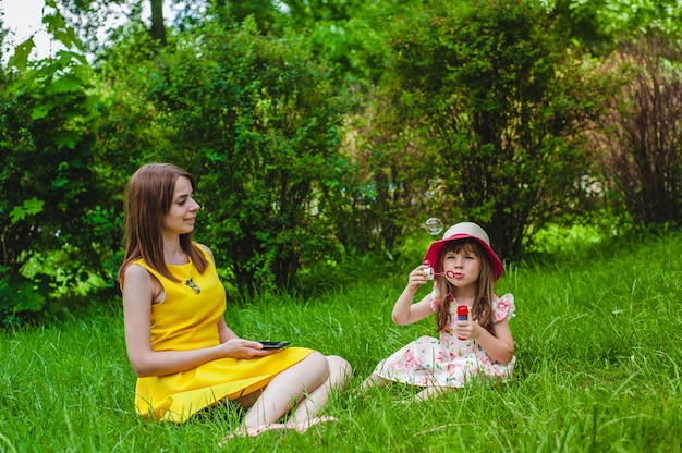 Mother watching as her daughter blows soap bubbles