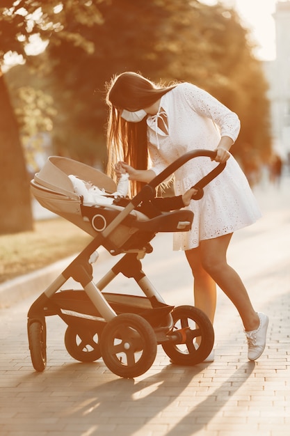 Mother wearing face mask.  Woman walking baby in stroller. Mom with baby pram during pandemic taking a walk outdoors
