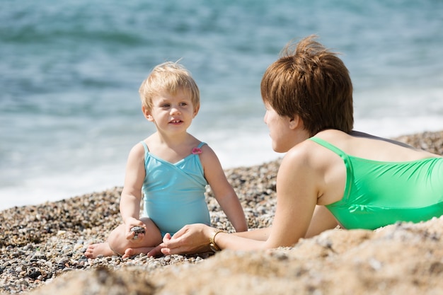 모래 해변에서 사랑스러운 유아와 어머니