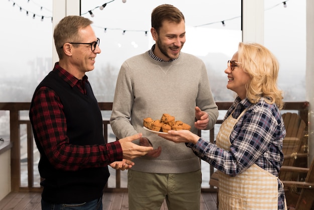 Foto gratuita madre con grembiule dando muffin a figlio e padre