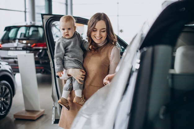 車を選ぶ赤ん坊の娘を持つ母親