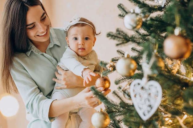 クリスマスツリーを飾る赤ん坊の娘を持つ母