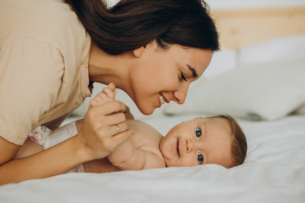 Free photo mother with baby daughter lying on bed