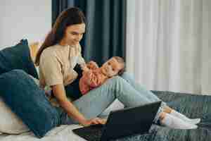 Free photo mother with baby girl working on computer from home