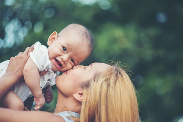 Free photo mother with baby, laughing and playing in the park