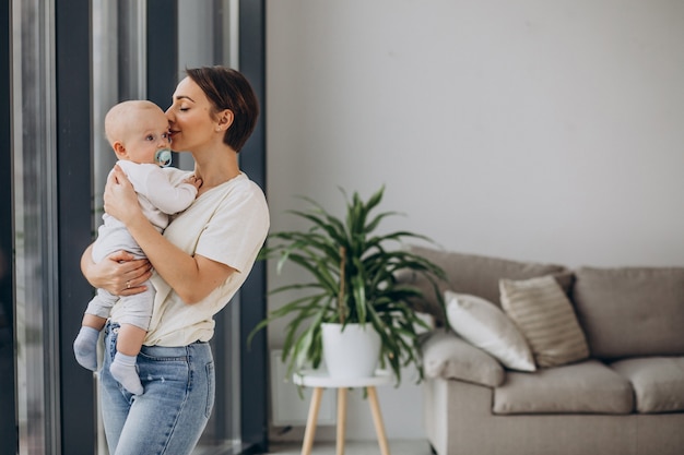 Mother with baby son standing at home by the window