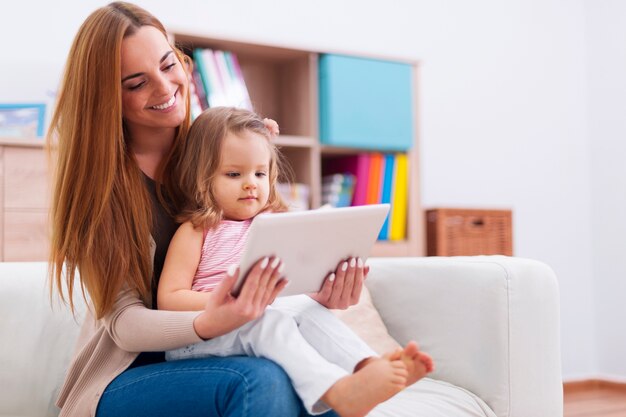 自宅でデジタルタブレットを使用して赤ちゃんを持つ母親