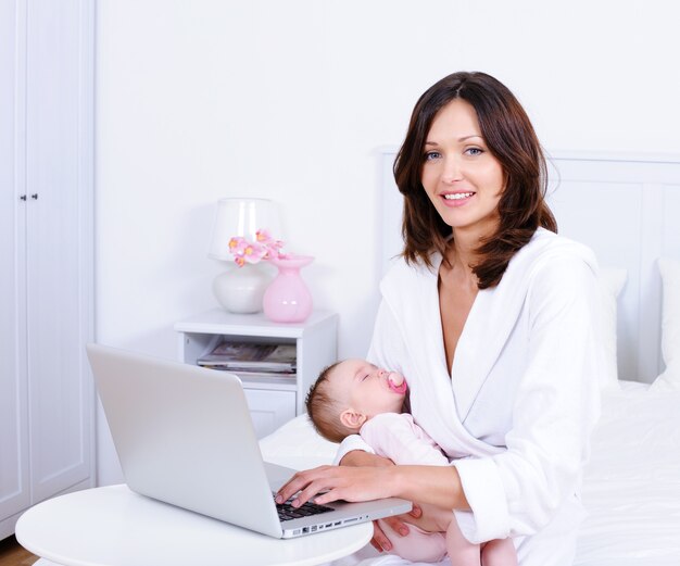 Mother with baby and with laptop at home