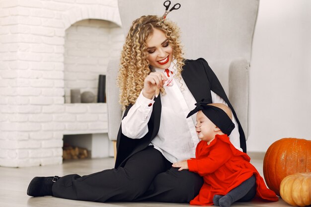 Mother with child in costumes and makeup. Family prepare to celebration of Halloween.