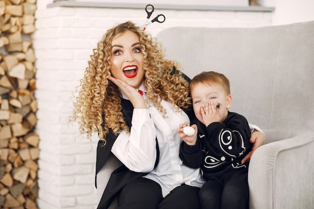 Mother with child in costumes and makeup. Family prepare to celebration of Halloween.