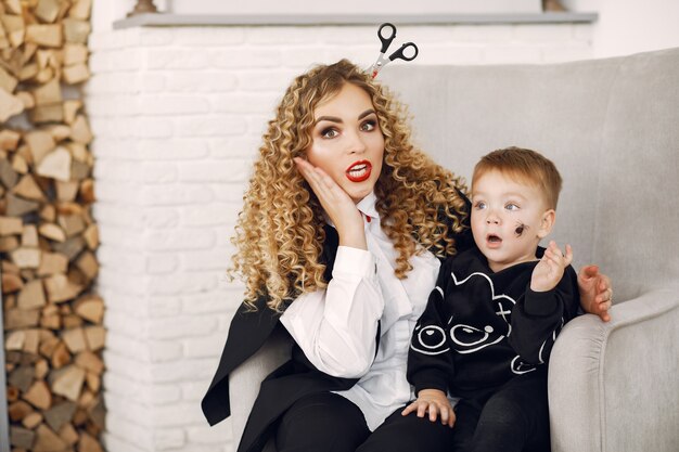 Mother with child in costumes and makeup. Family prepare to celebration of Halloween.