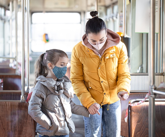 A mother with a child in an empty public transport, wearing masks during a pandemic. Coronavirus.