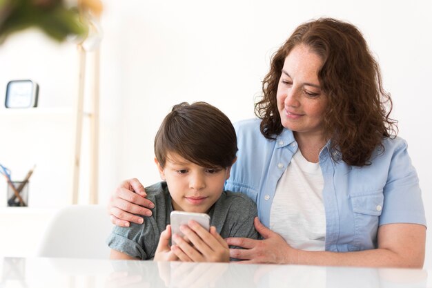 スマートフォンで見ている子供を持つ母