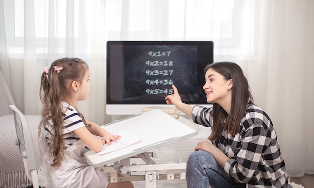 Una madre con un bambino si siede a tavola e fa i compiti.