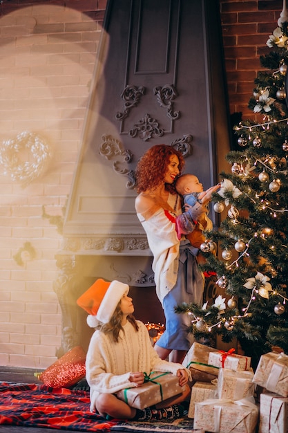 クリスマスツリーを飾る子供を持つ母