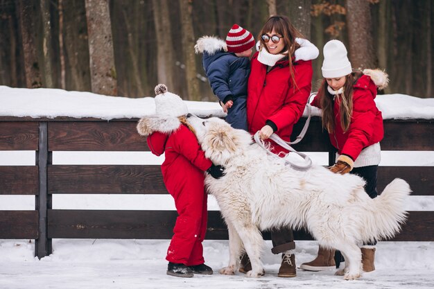 Mother with children and dog playing outside in winter