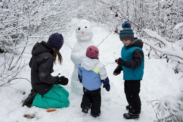 Mother with children making snowman