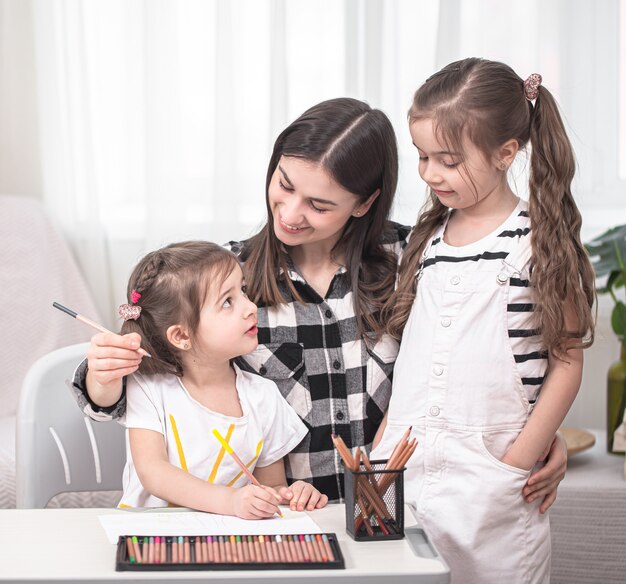 Mother with children sitting at the table and doing homework. The child learns at home. Home schooling. Space for text.