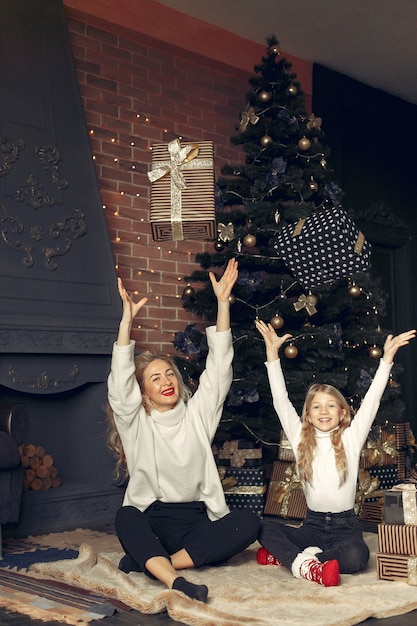 Mother with cute daughter at home near christmas tree