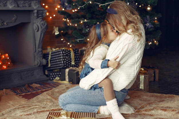 Mother with cute daughter at home near fireplace