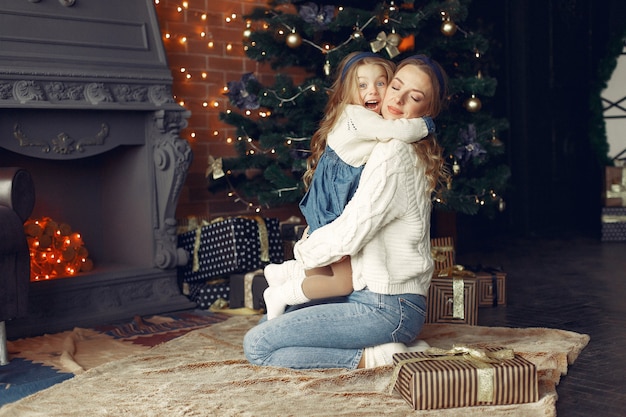 Mother with cute daughter at home near fireplace