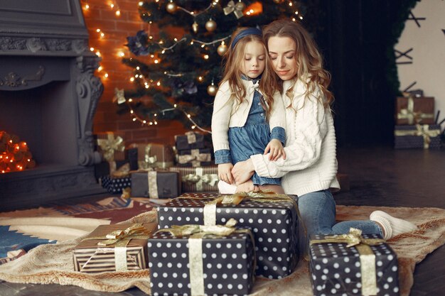 Mother with cute daughter at home near fireplace