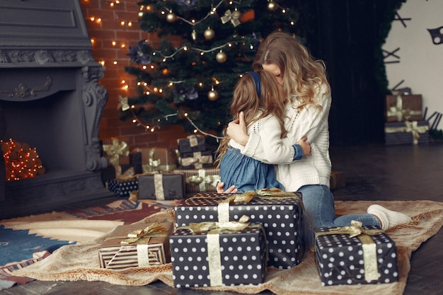 Mother with cute daughter at home near fireplace