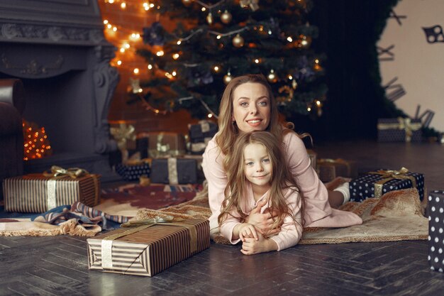 Mother with cute daughter at home near fireplace