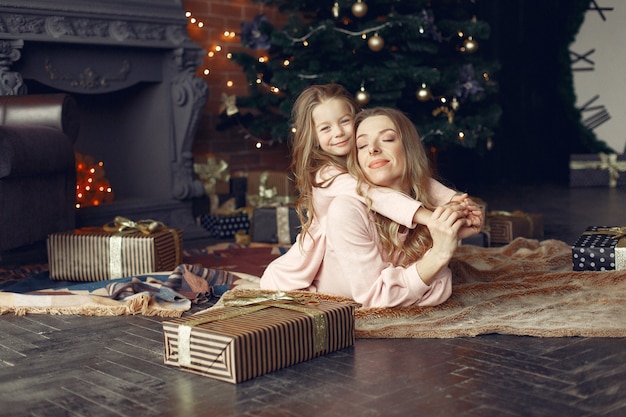 Mother with cute daughter at home near fireplace