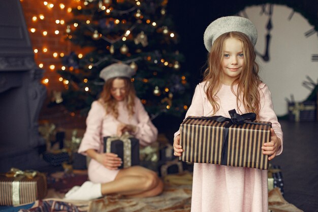 Mother with cute daughter at home near fireplace