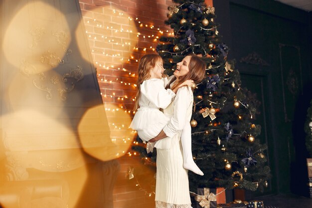 Mother with cute daughter at home near fireplace