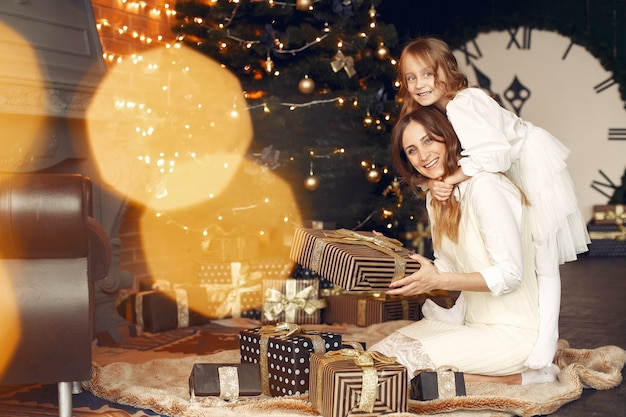 Mother with cute daughter at home near fireplace