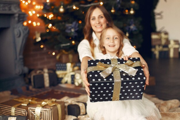 Mother with cute daughter at home near fireplace