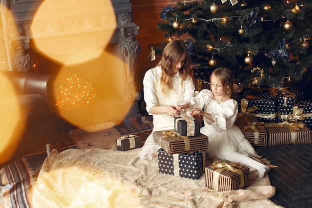 Mother with cute daughter at home near fireplace