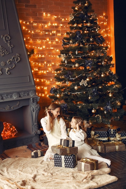 Mother with cute daughter at home near fireplace
