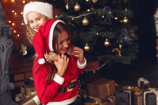 Mother with cute daughter at home near fireplace