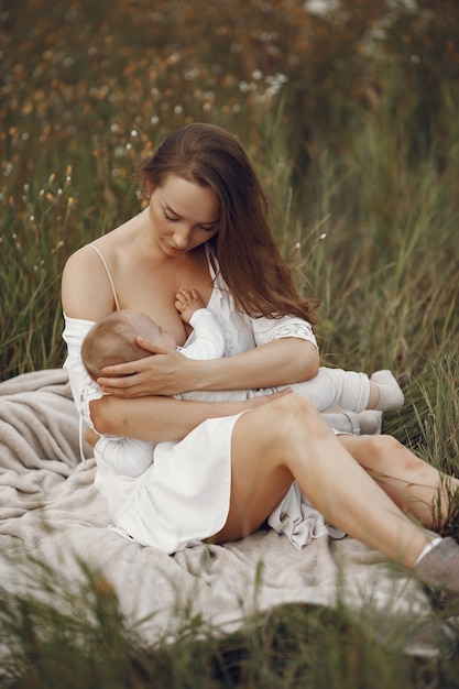 무료 사진 귀여운 딸과 어머니입니다. 그녀의 작은 딸을 모유 수유하는 엄마. 흰 드레스에 여자입니다.