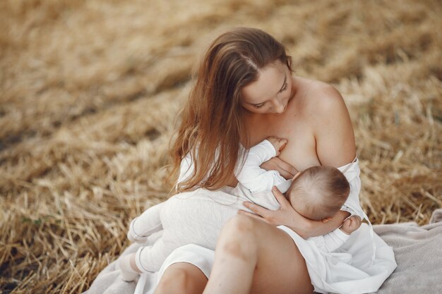 Мать с милой дочерью. Мама кормит свою маленькую дочь грудью. Женщина в белом платье.