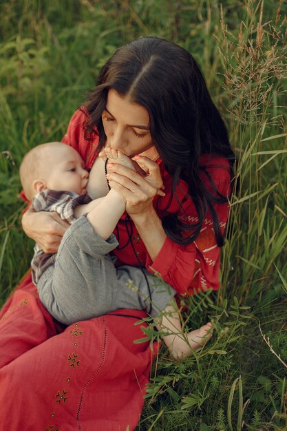 Mother with cute daughter. Mom breastfeeding her little son. Woman in a red dress.