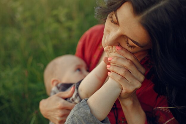 かわいい娘を持つ母。彼女の幼い息子を母乳で育てるママ。赤いドレスを着た女性。