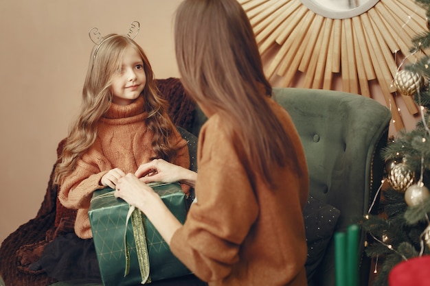 Mother with cute daughter near christmas tree