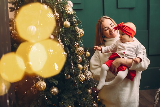 Mother with cute daughter near christmas tree